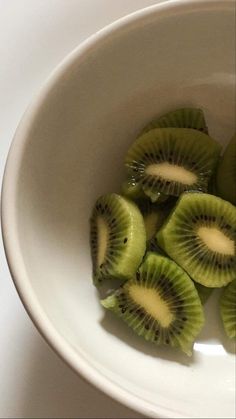 sliced kiwis in a white bowl on a table