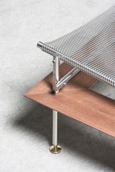 a close up of a metal and wood bench on concrete floor with light colored background