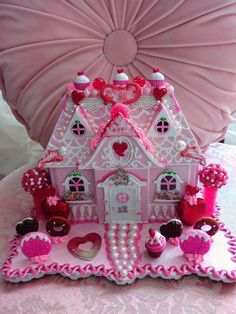 a pink and white doll house sitting on top of a table next to a pillow