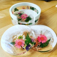 two plates with flowers on them sitting on a table next to a bowl filled with water