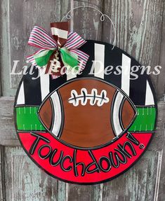 a door hanger with a football painted on it and the words touch down written in red, green, and black