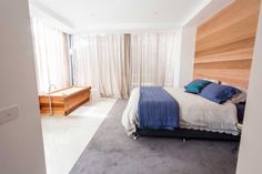 a bedroom with a large bed and wooden headboard on the wall next to a window