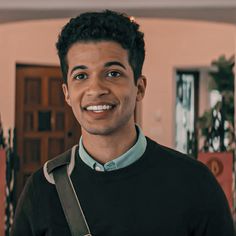 a man standing in front of a doorway with a camera around his neck and looking at the camera