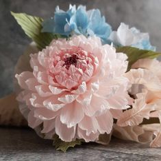 three pink and blue flowers sitting on top of a table