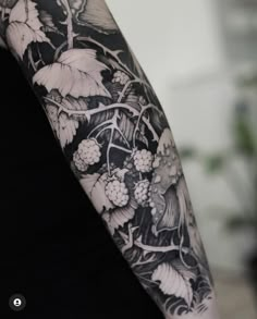 a woman's arm with flowers and vines tattooed on her left arm, in black and white