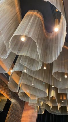 the lights are hanging from the ceiling in the building's lobby, which is decorated with sheer fabric