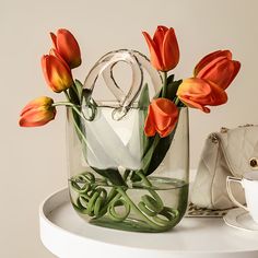 a vase with flowers in it sitting on top of a table next to a purse