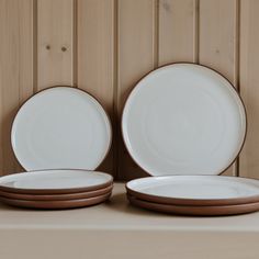 two white and brown plates sitting on top of a table next to each other in front of a wood paneled wall