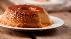 a bundt cake on a white plate sitting on a wooden table next to other pastries