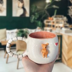 a hand holding a coffee mug with a teddy bear on it