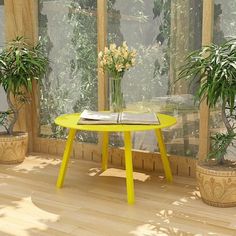 a yellow table sitting in front of two potted plants