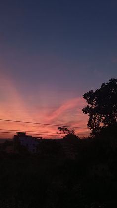 the sun is setting over some trees and buildings