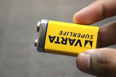 a person holding a yellow battery in their hand