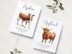 two cards with pictures of cows on them are shown next to flowers and greenery