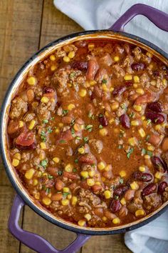 a pot filled with chili and corn on top of a wooden table