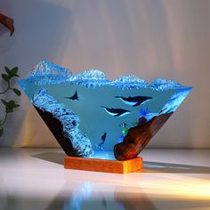 a glass bowl that is sitting on top of a wooden stand with an ocean scene in it