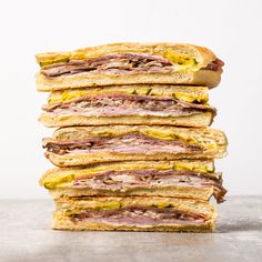 a stack of sandwiches sitting on top of each other in front of a white wall