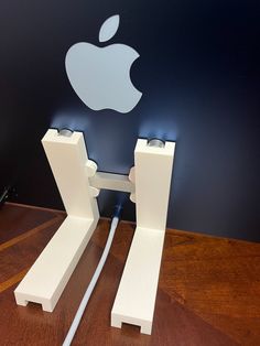 an apple logo is shown on the wall behind two pieces of white plastic that are connected to each other