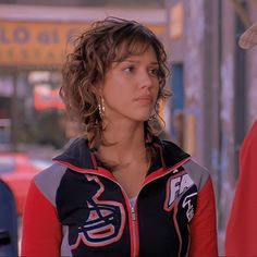 a woman with curly hair wearing a black and red jacket