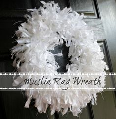 a close up of a wreath on a door with white feathers hanging from the front