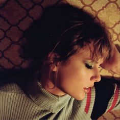 a woman laying on the floor with her eyes closed and looking down at something in front of her