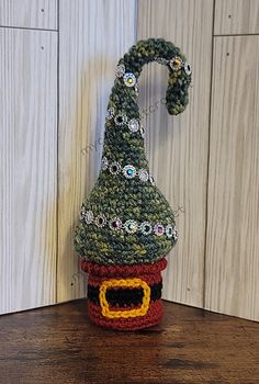 a crocheted gnome's hat sitting on top of a wooden table next to a wall