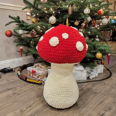 a crocheted mushroom sitting in front of a christmas tree