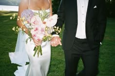 the bride and groom are walking through the grass