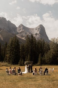 a wedding ceremony in the mountains with people sitting on chairs and looking at each other