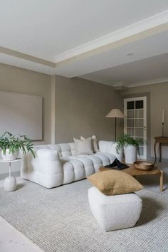 a living room filled with white furniture and plants