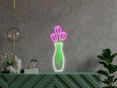 a vase with flowers is lit up on a table next to a plant and lamp