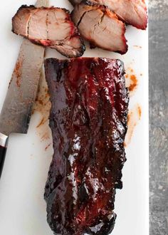 sliced meat on a cutting board next to a knife