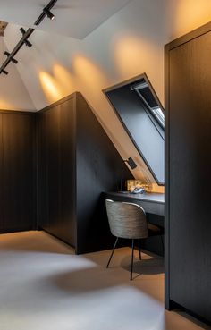 an attic bedroom with dark wood paneling and white walls, along with a desk in the corner