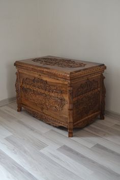 a wooden chest sitting on top of a hard wood floor next to a white wall