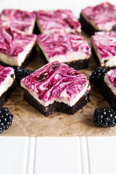 there are many desserts on the table with blackberries and raspberry topping