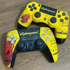 two yellow video game controllers sitting on top of a wooden table next to each other