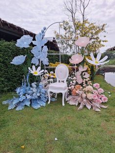 a chair sitting on top of a lush green field next to lots of flowers and plants