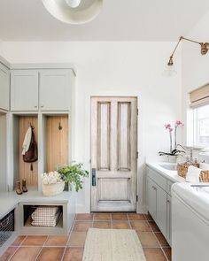 a kitchen with white cabinets and tile flooring next to a washer and dryer