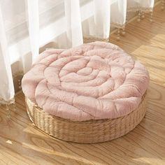 a round bed sitting on top of a wooden floor next to a white curtained window