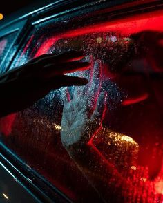 a person is washing their hands in the car's rear window with red light