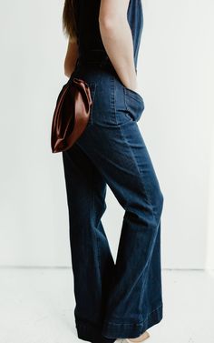 Saddle up in style with our Long Flared Denim Jumpsuit. Its flattering silhouette and tan contrast stitching add Western vibes to any outfit. Perfectly paired with boots and a cowboy hat for a playful, unique look. Yee-haw! Fitted Dark Wash Flare Jeans With Contrast Stitching, Fitted Flare Jeans With Contrast Stitching, Chic Dark Wash Straight Leg Denim Jumpsuit, Spring Flare Jeans With Contrast Stitching In Medium Wash, Denim Bottoms With Contrast Stitching For Fall, Denim Blue Flare Jeans With Contrast Stitching For Spring, Fitted Bottoms With Contrast Stitching For Fall, Fall Denim Bottoms With Contrast Stitching, Fitted High Rise Western Flare Jeans