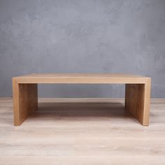 a wooden table sitting on top of a hard wood floor next to a gray wall