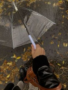 a person holding an umbrella in the rain with their feet propped up on the ground