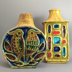 two ceramic vases sitting next to each other on a gray surface with different designs