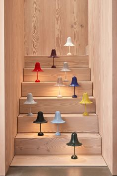 several different colored lamps are on the stairs in this room with wooden walls and flooring