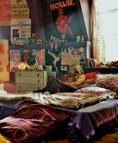 a woman is laying on her bed in front of a window with posters above it