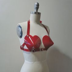 This bullet bra, or "cone bra" is inspired by retro pin-up vixens. This is the-heart-shaped version! Wear alone or layered and add a touch of drama to any outfit. Halter style straps. Buckles in front, back, and behind the neck. Silver-toned nickel plated hardware. Available in PVC, leather, and black vegan leather. Fits up to a DD cup - custom sizing available for larger cup sizes in leather, vegan leather, and clear PVC. Shown in white, clear, and red PVC. ** This is sized according to the siz