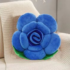 a blue flower shaped pillow sitting on top of a white couch next to a window