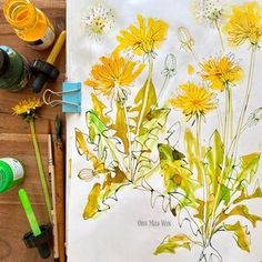 some yellow flowers are sitting on a table next to water bottles and paintbrushes