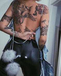 a woman with tattoos on her back holding a purse